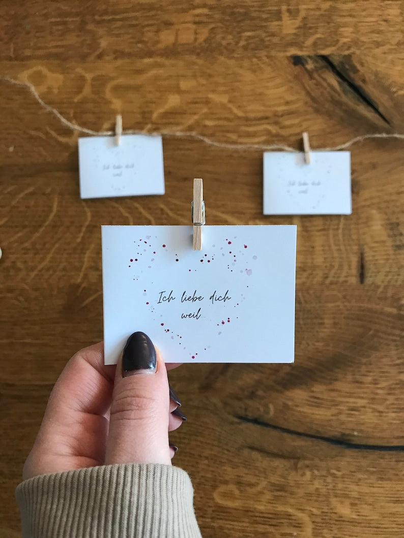 Einzelne handgemalte „Ich liebe dich, weil …“-Kärtchen mit Herzmotiv.