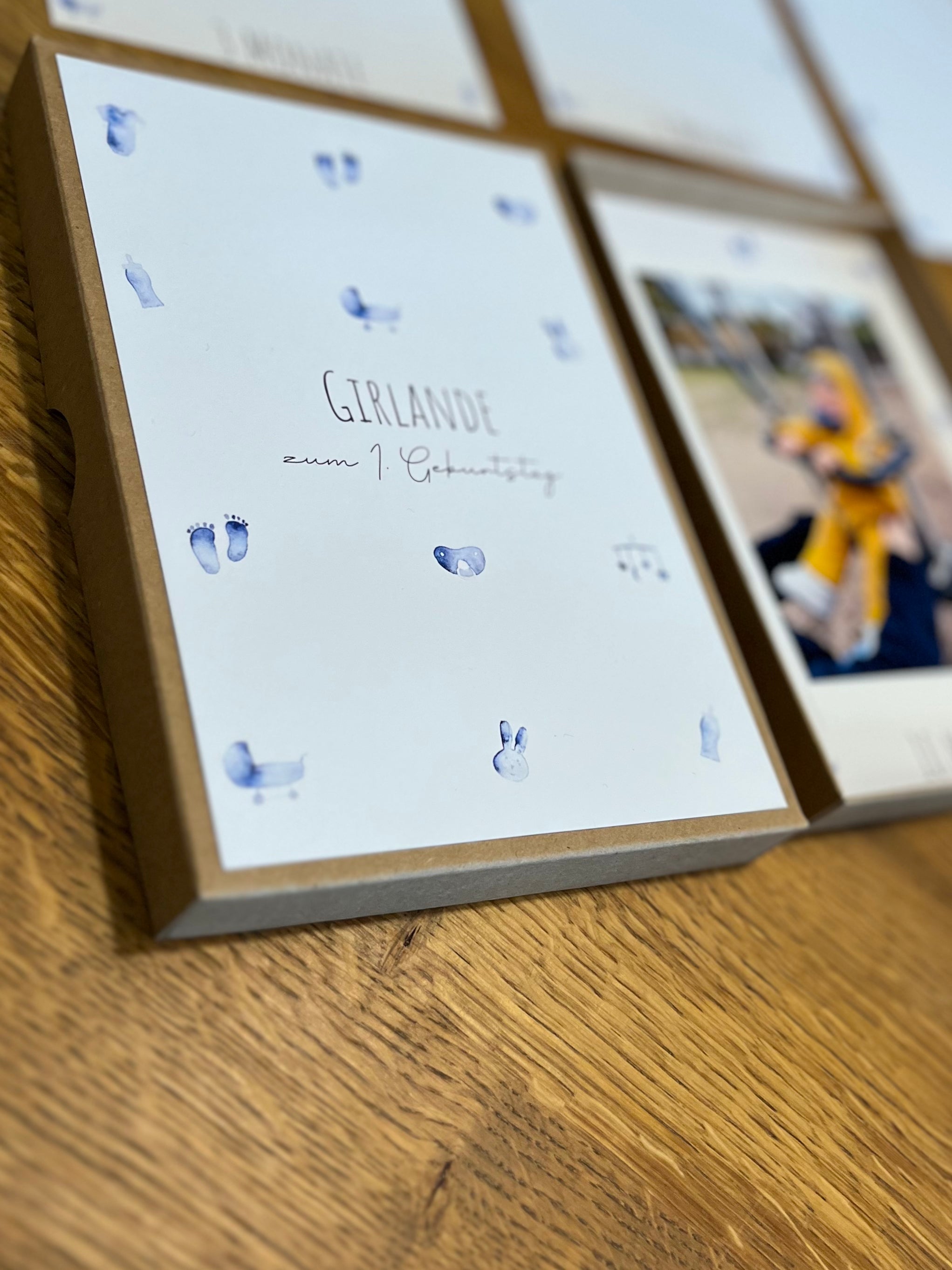Handgemachte Fotogirlande für den 1. Geburtstag mit blauen Babymotiven, Klammern, Juteschnur, Box und Karten für Babyfotos.