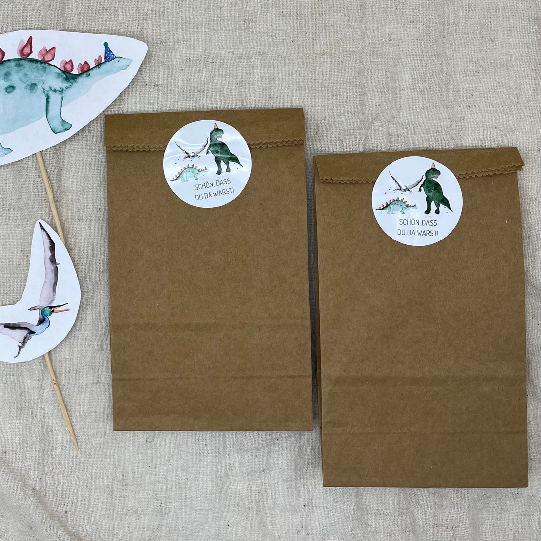 Runde Dino-Sticker „Schön, dass du da warst“ auf einer Gastgeschenktüte zum Kindergeburtstag.