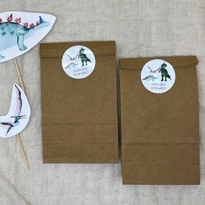 Runde Dino-Sticker „Schön, dass du da warst“ auf einer Gastgeschenktüte zum Kindergeburtstag.